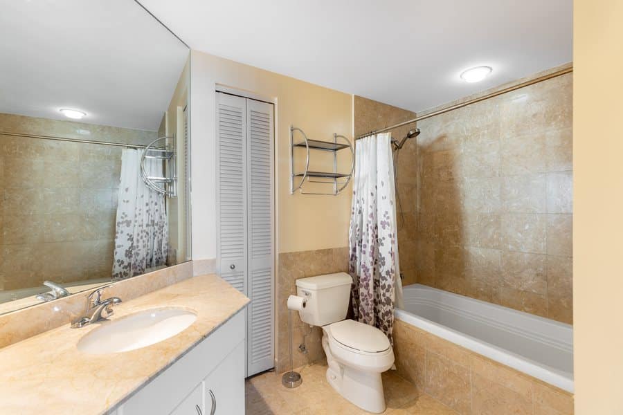 Bathroom with a vanity, mirror lighting and a tub with shower curtain
