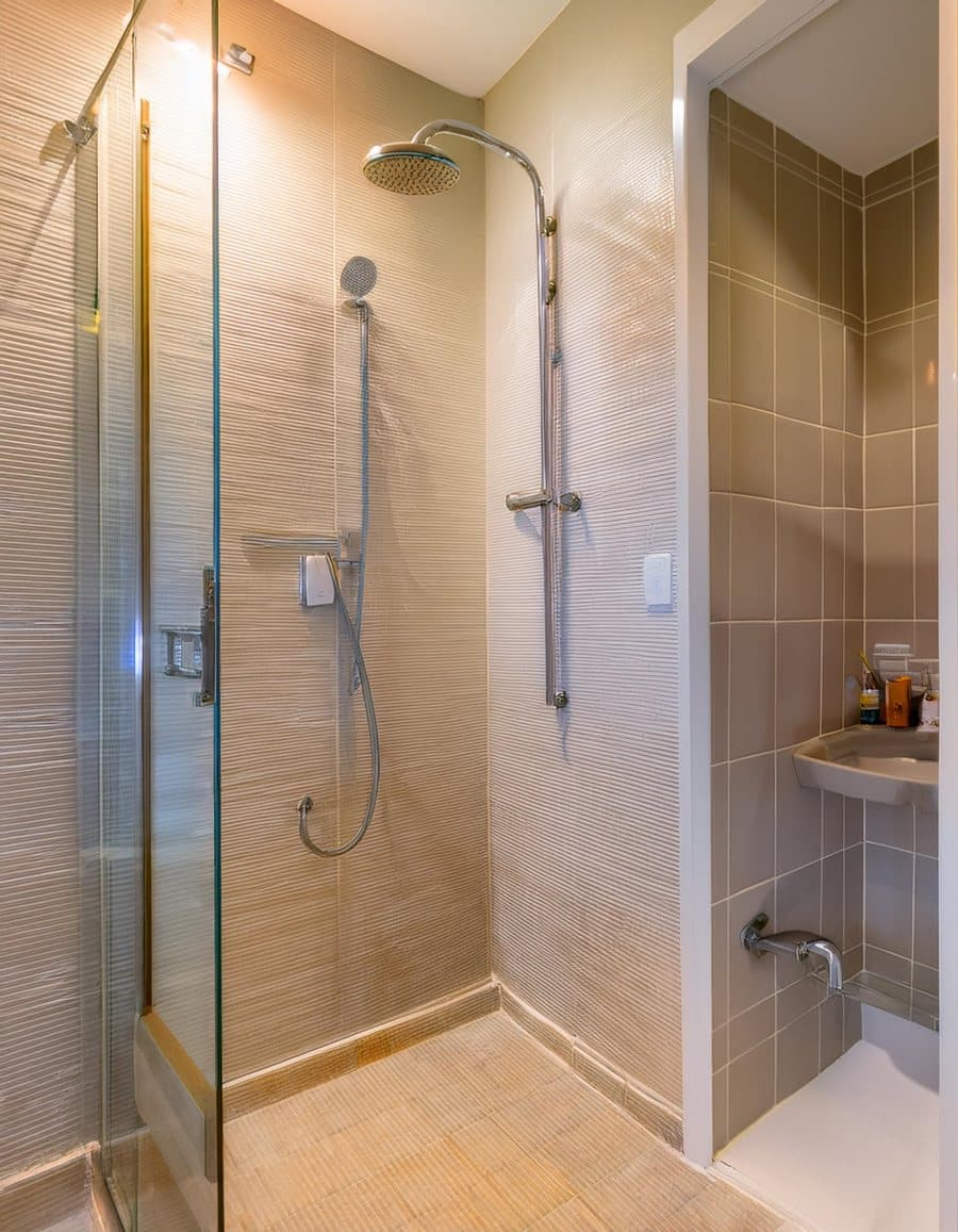 Walk-in glass shower with a handheld shower head and tiled walls
