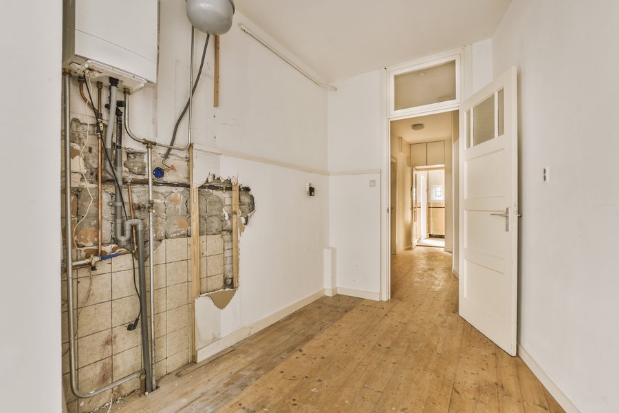 Room stripped for renovation with exposed plumbing and new wood floors