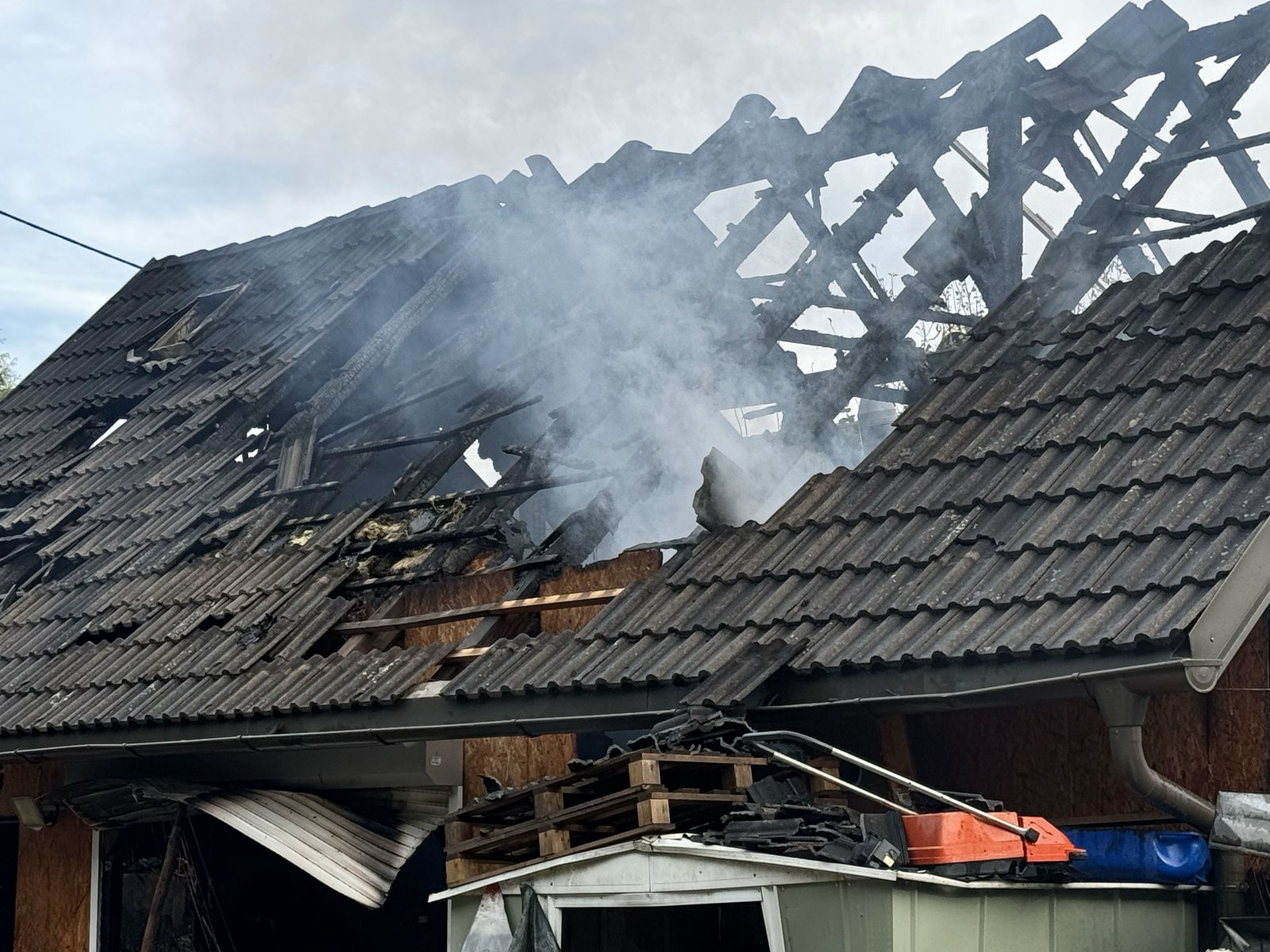 Fire-damaged roof with smoke rising from the collapsed structure