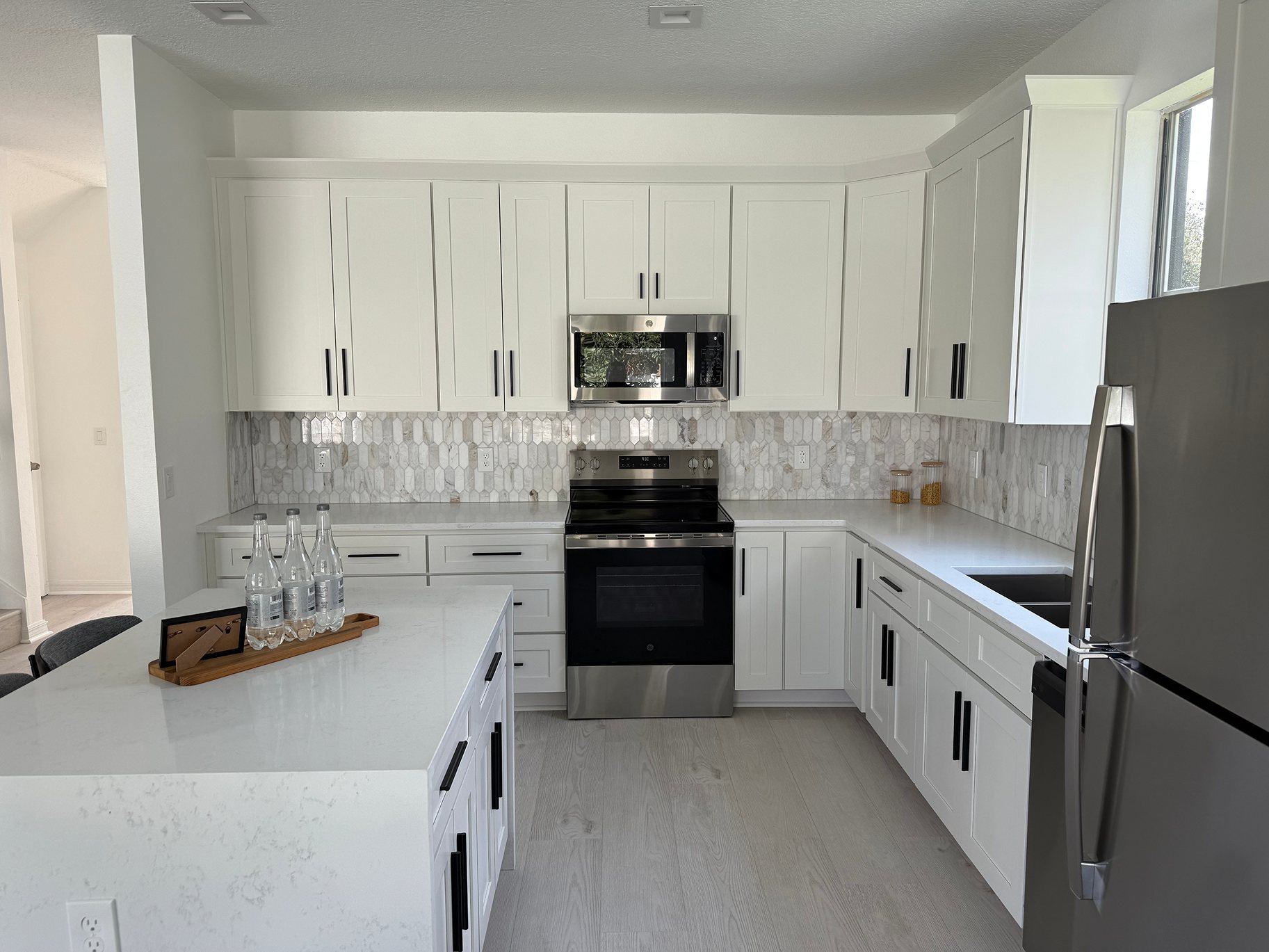 White kitchen with shaker cabinets, stainless appliances and a tiled floor